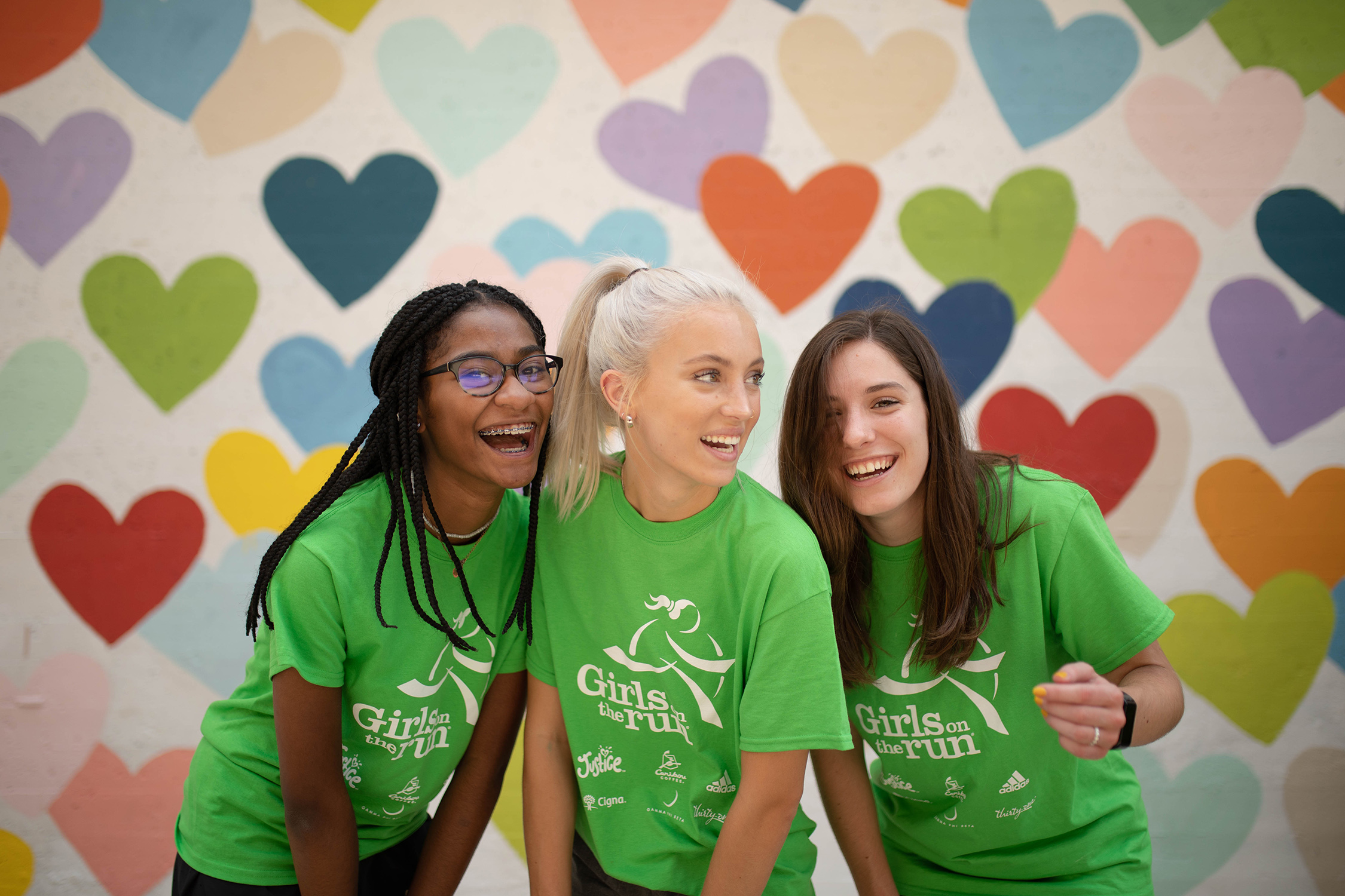Three girls wearing green shirts and smiling.