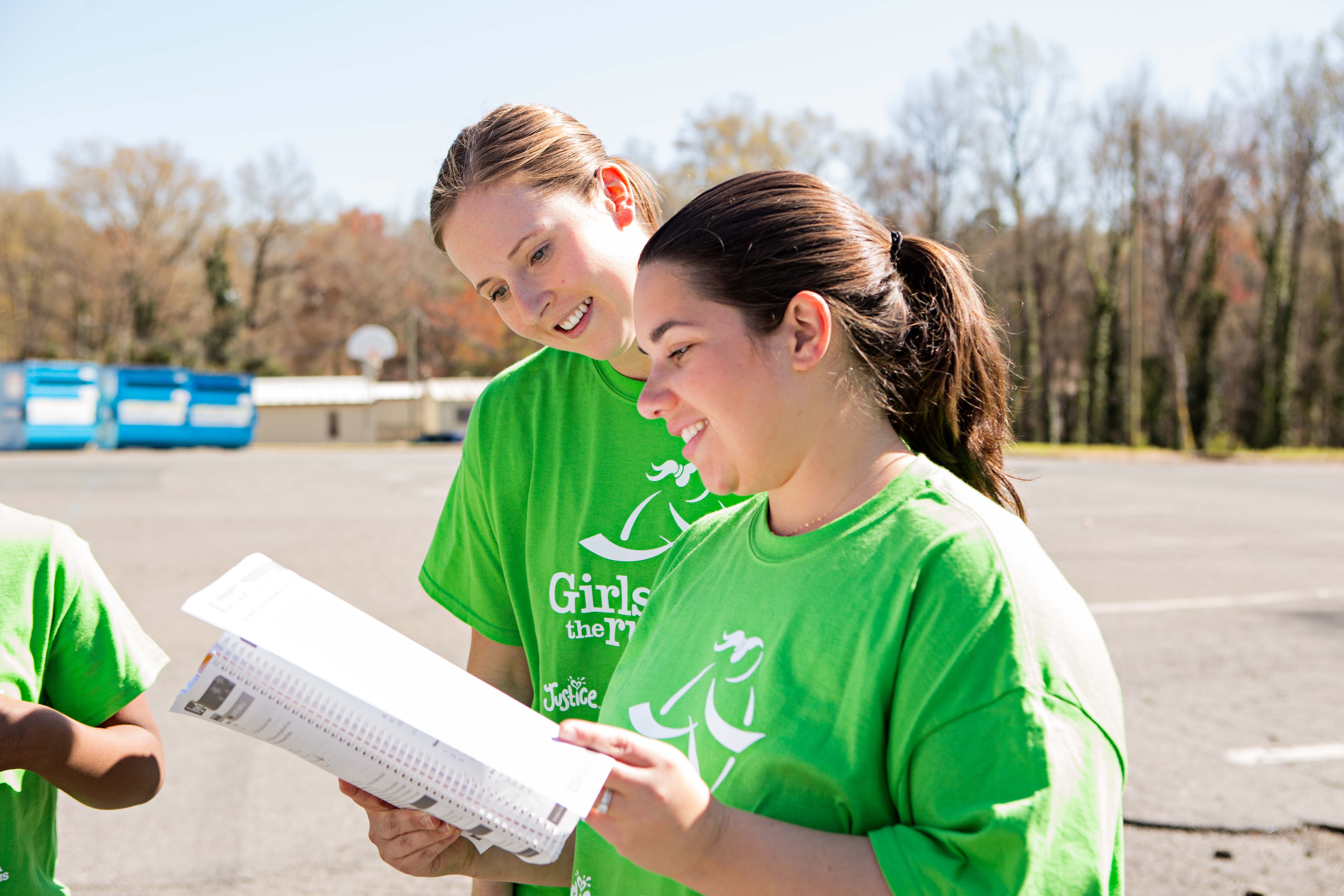 Two Girls on the Run coaches smiling as they read lesson