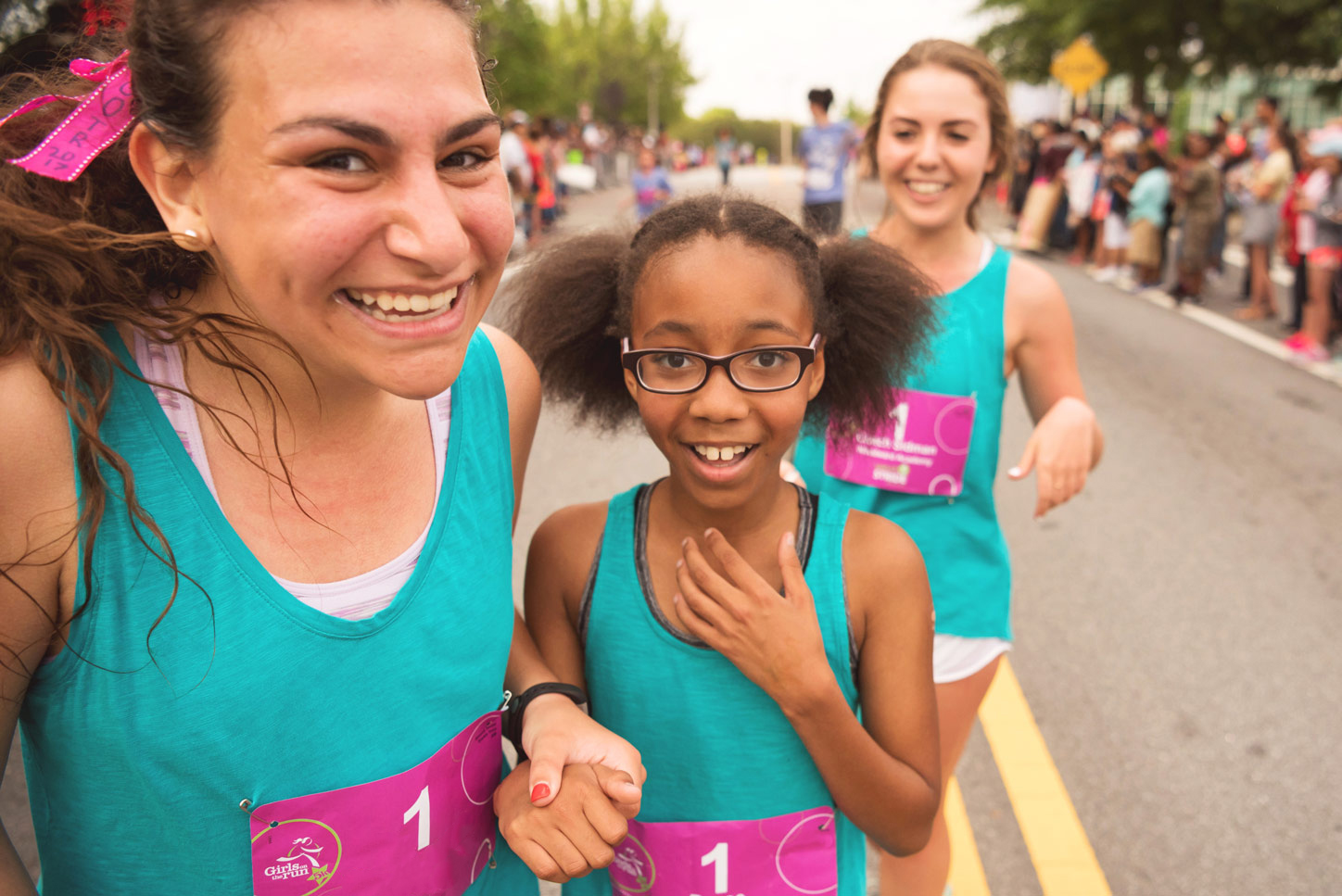 Girls on the Run Coach and participant both smile while holding hands at 5K 